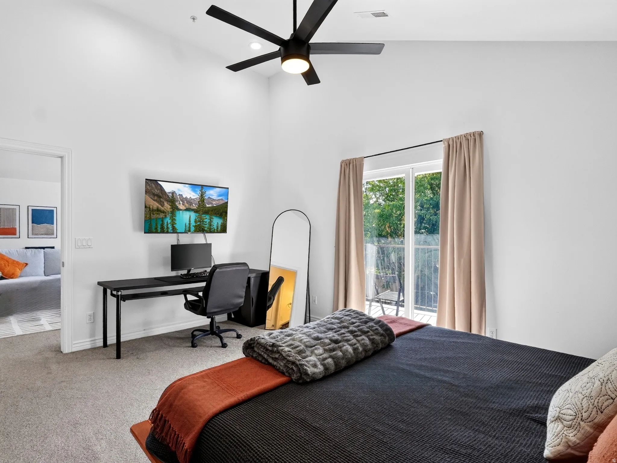 Spacious primary bedroom with carpet flooring, ceiling fan with integrated lighting, and glass sliding door access to outdoor space
