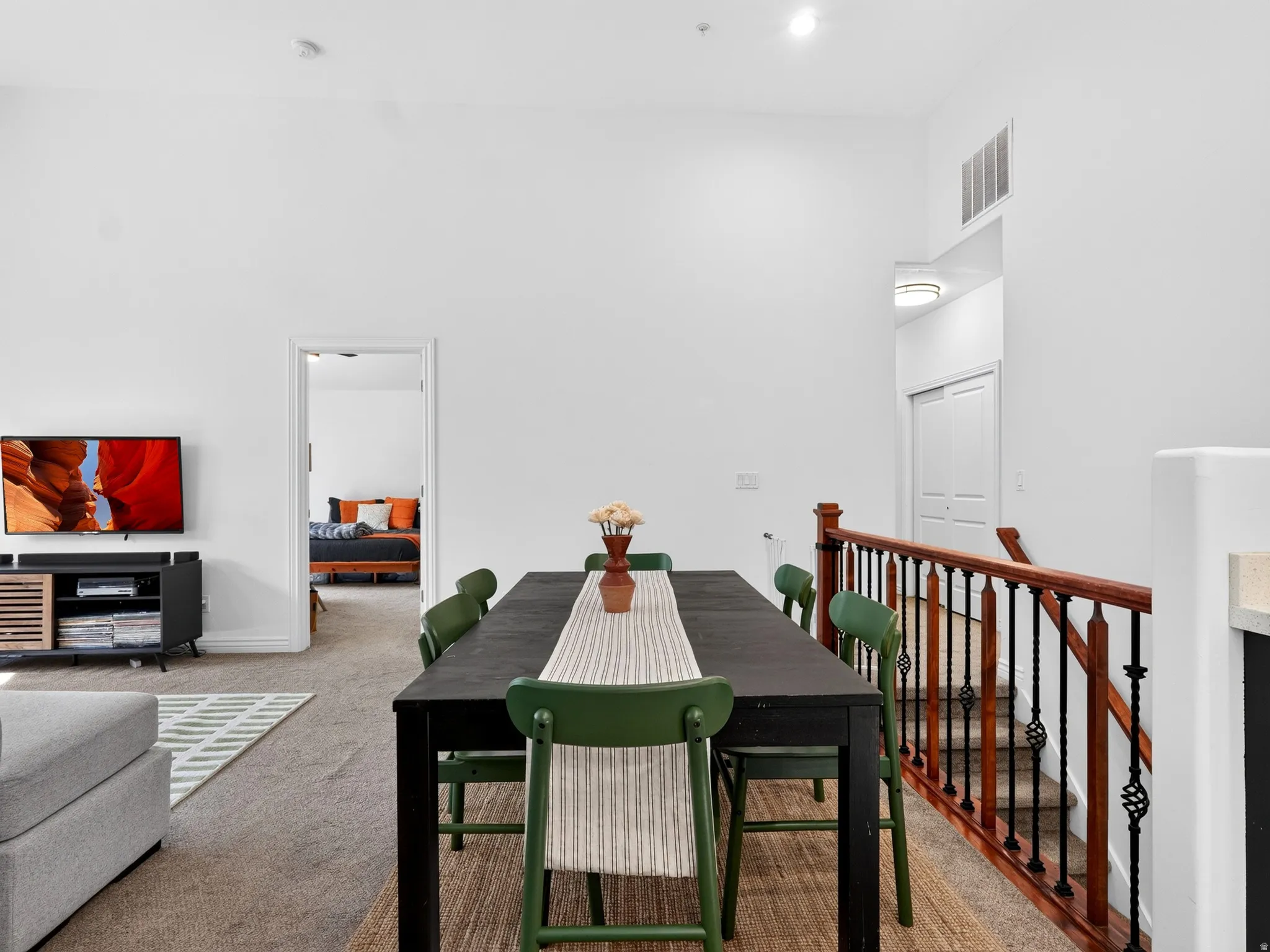 Open-concept living space featuring a black dining table with striped upholstered chairs, wood-finish flooring, and recessed ceiling lighting