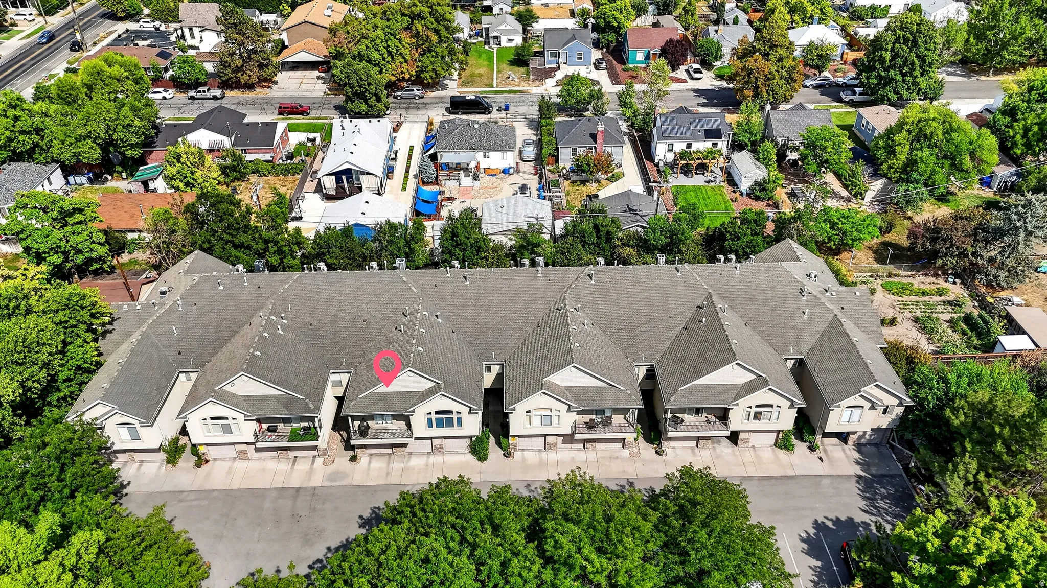Aerial view showcasing a striking row of five residential units with coordinated gray asphalt roofing, white exterior finishes, and distinctive architectural detailing