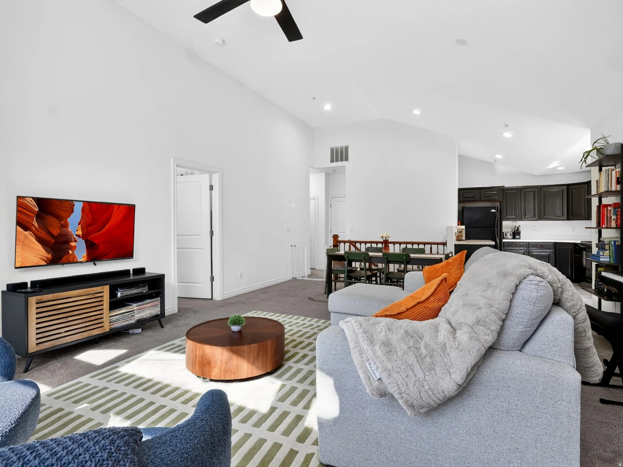 Open-concept living space featuring a ceiling fan, recessed lighting, and a wood-finish media console with slatted storage