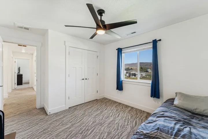 White walls, a ceiling fan with integrated lighting, and a window framing a distant mountainous landscape