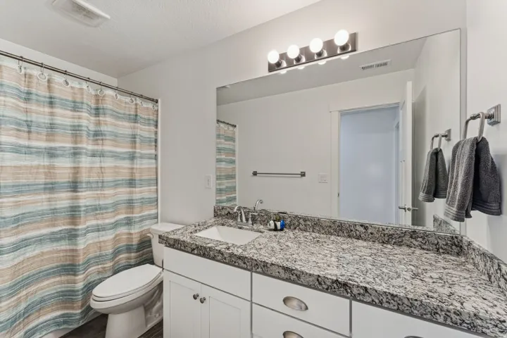 White vanity with dual sinks, speckled countertop, and brushed nickel hardware