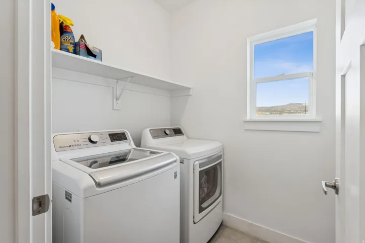 Laundry area with a built-in shelf, white walls, and a single window