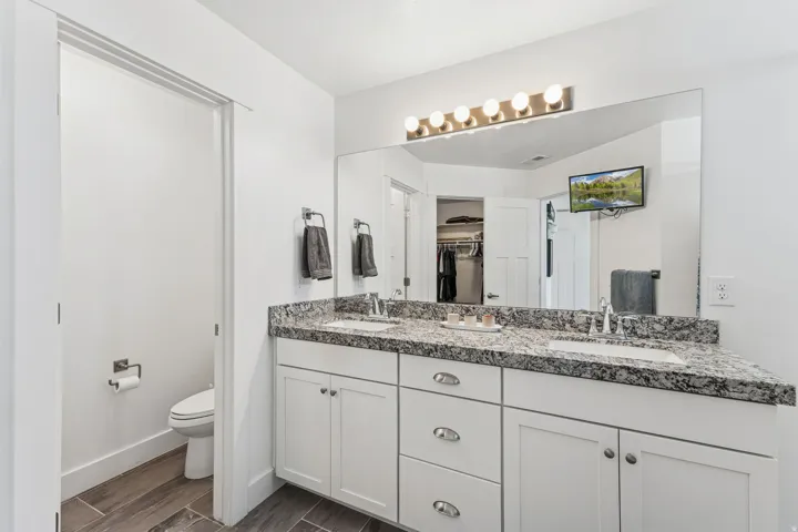 Dual vanity with undermount sinks, granite countertop, and white cabinetry