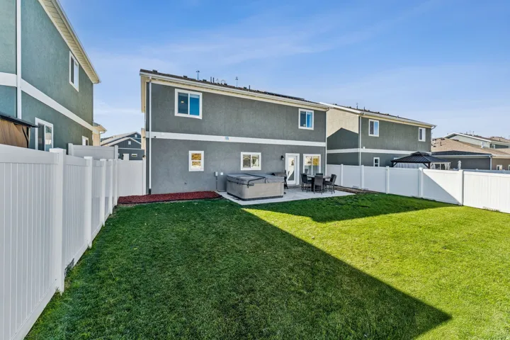 Expansive backyard featuring a manicured lawn, a large concrete patio, and a privacy fence