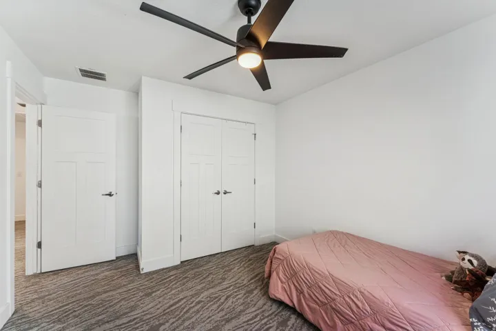 White walls, ceiling fan with integrated lighting, patterned carpet, white interior doors, and white bi-fold closet doors
