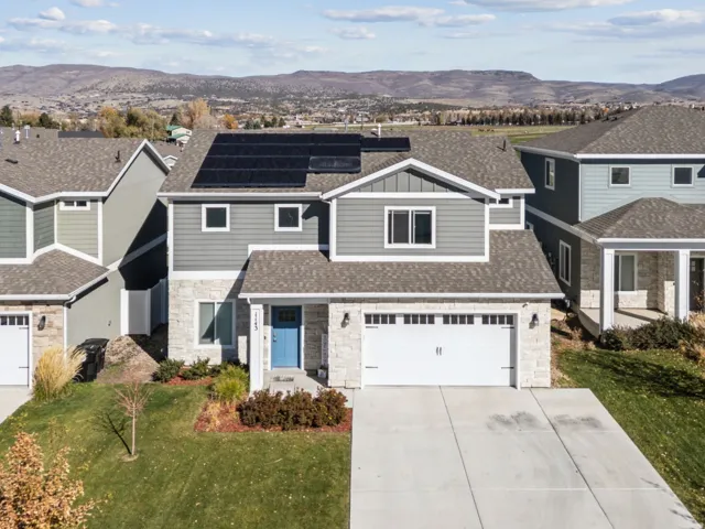 Two-story residence featuring a gray exterior with stone accents, a two-car garage, and a blue entry door
