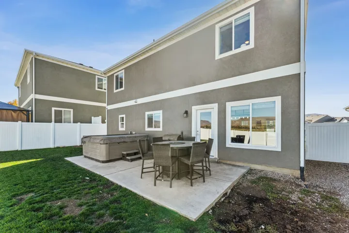 Backyard featuring a concrete patio, hot tub, and white privacy fence