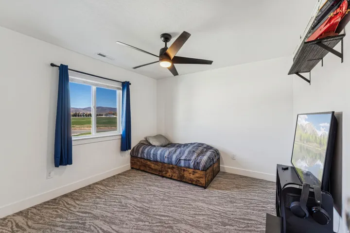 Room featuring a window with expansive outdoor scenery, a ceiling fan with integrated lighting, and wall-mounted shelving