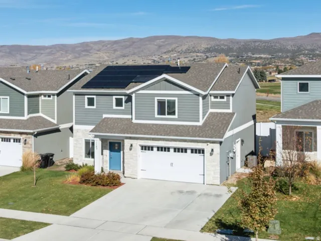 Modern exterior with solar panels, two-car garage, manicured lawn, and concrete driveway