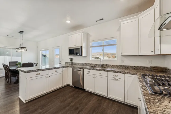 Kitchen featuring white cabinetry, stone countertops, stainless steel appliances, wood-finish flooring, and recessed lighting