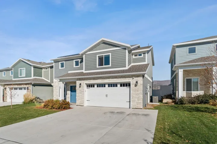 Contemporary exterior with stone accents and horizontal siding, featuring an attached garage with a double door, a blue entry door, and solar panels