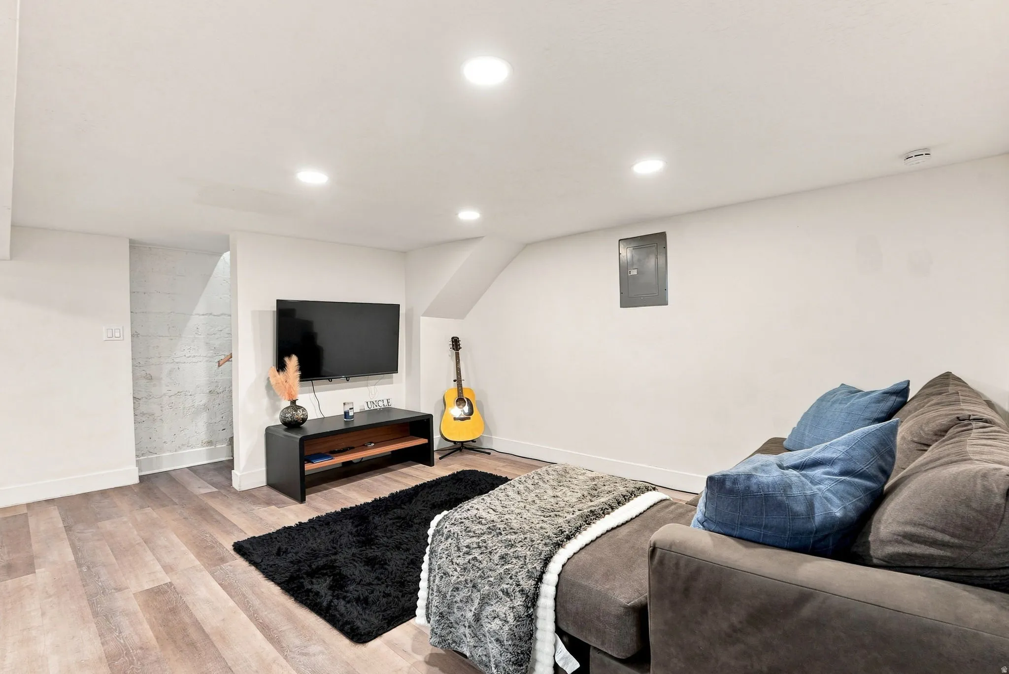 Recessed ceiling lighting, wood-finish flooring, white walls, and a built-in media console