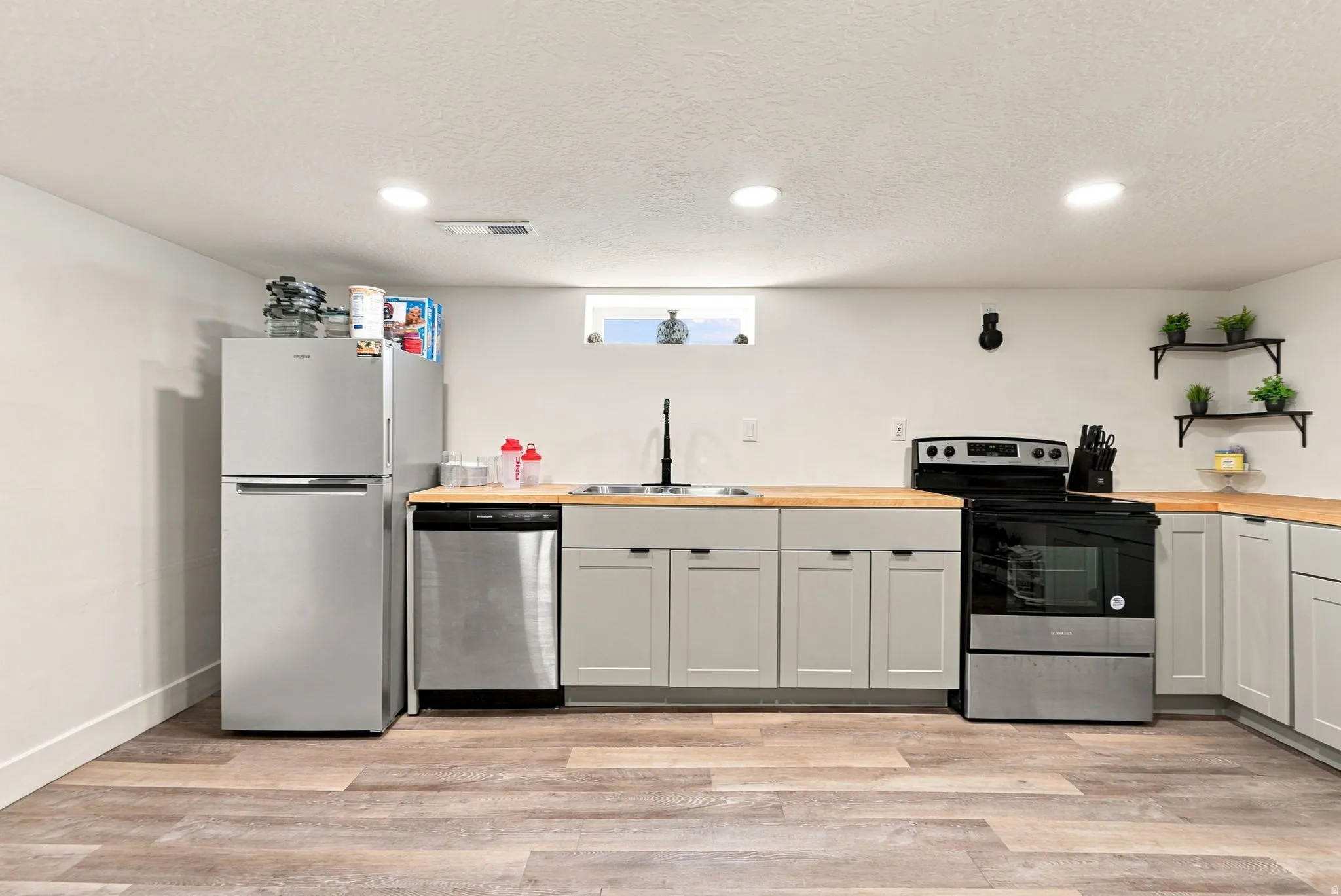 Kitchen featuring wood-finish flooring, light gray cabinetry, stainless steel appliances, butcher block countertops, and recessed lighting
