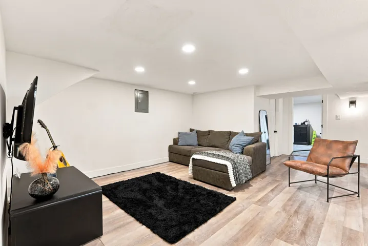 Recessed ceiling lighting, wood-finish flooring, white walls, and a wall-mounted light fixture