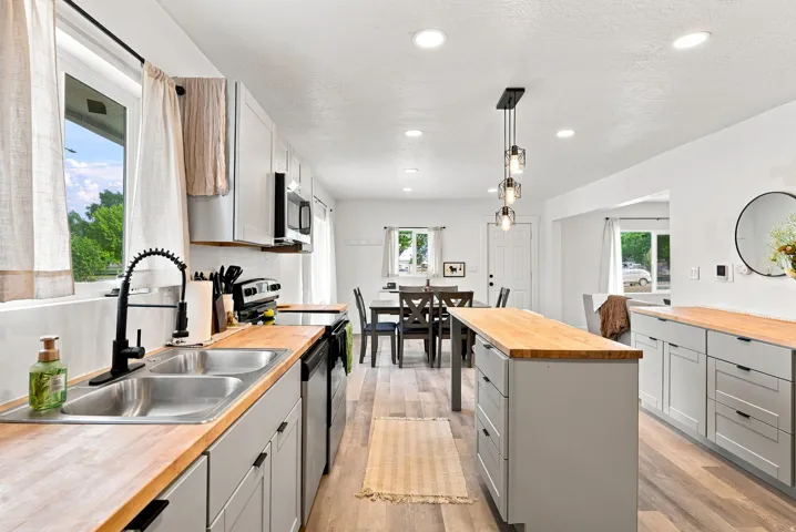 Light wood-finish flooring, recessed lighting, and a kitchen island with butcher block countertop
