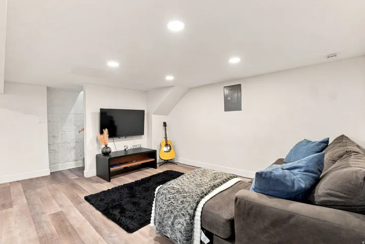 Recessed ceiling lighting, wood-finish flooring, white walls, and a built-in media console