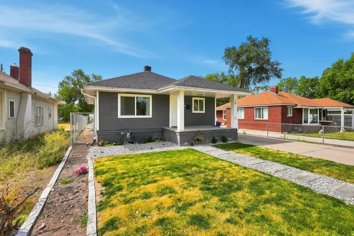 Modern exterior siding, covered front porch with white columns, asphalt shingle roof, concrete and gravel walkway, and a landscaped front yard