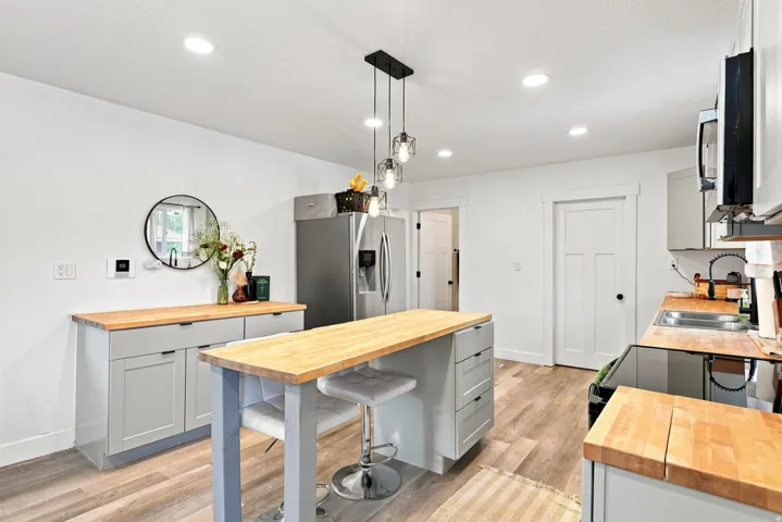 Kitchen featuring wood-finish flooring, butcher block countertops, light gray cabinetry, stainless steel appliances, and recessed lighting