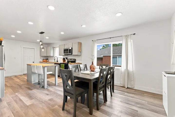 Open-concept kitchen and dining area featuring wood-finish flooring, recessed lighting, and a kitchen island with wood countertop