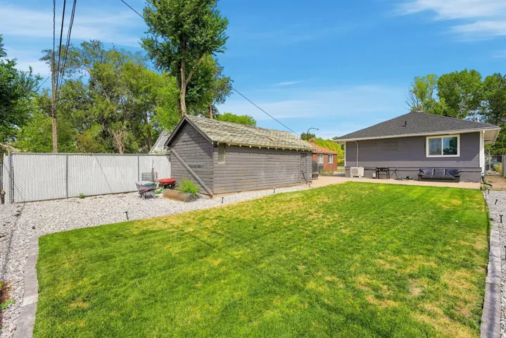Expansive backyard featuring a manicured lawn, a detached storage building, and a chain-link fence