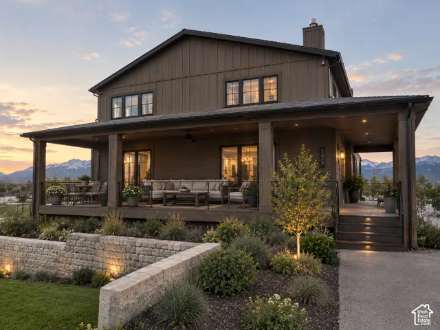 Two-story residence featuring board and batten siding, a full-length covered porch, and integrated outdoor lighting