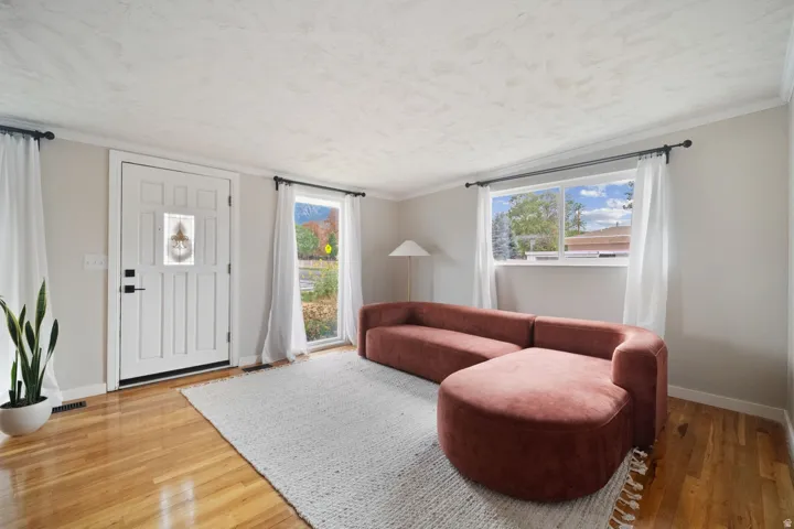 Wood-finish flooring throughout, white paneled door, and multiple windows allowing natural light