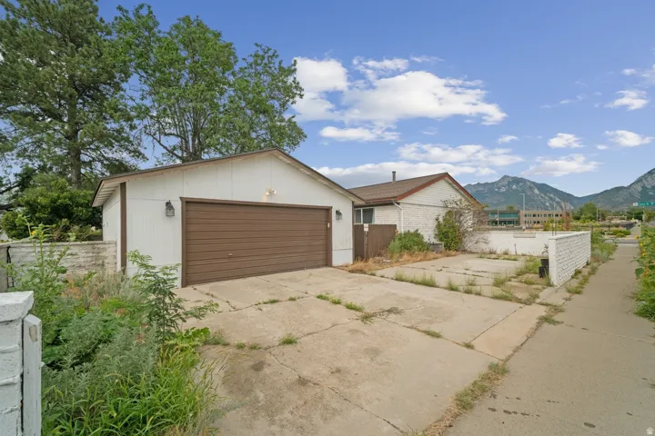 Detached garage with a brown door, concrete driveway, and a white brick perimeter wall