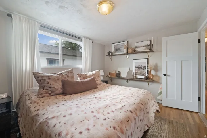 Hardwood flooring, sconce lighting, white trim, wood-finish shelving, and a three-panel interior door