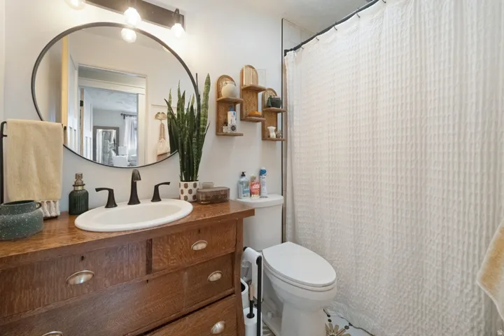 Wood-finish vanity with an integrated oval sink, matte black faucet, and an oval framed mirror