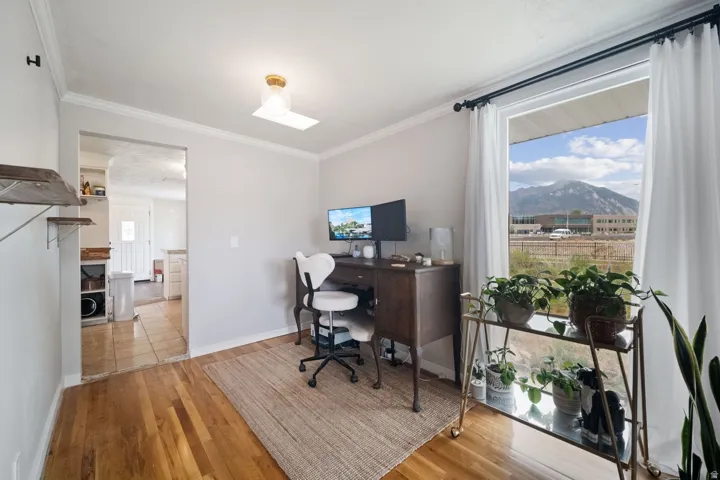 Hardwood flooring, crown molding, cased arched opening, recessed lighting, and a large window