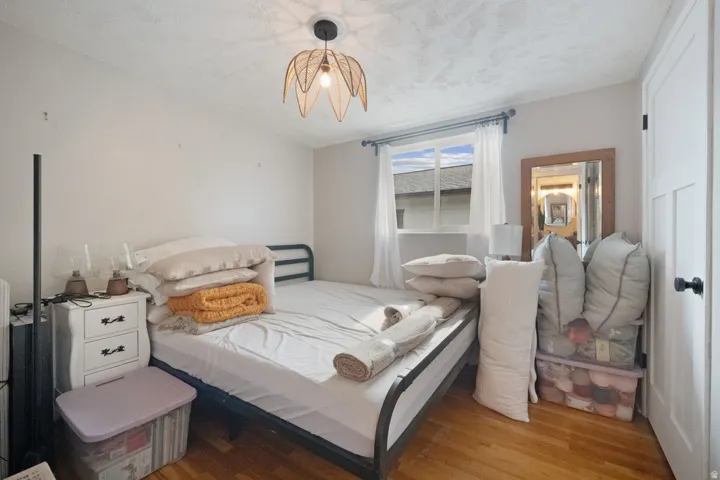 Hardwood flooring, single window with white curtains, and a ceiling-mounted light fixture
