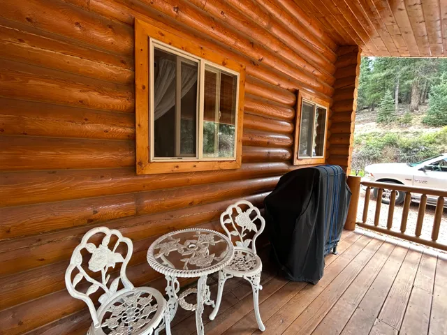 Log cabin exterior featuring a covered porch with wood flooring and wood railing