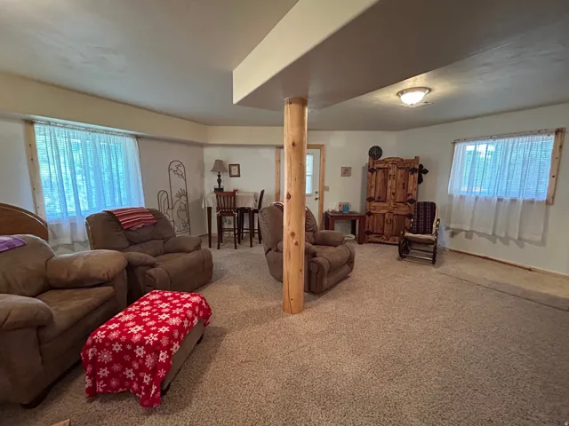 Carpeted room with a wooden structural column, recessed lighting, and multiple windows