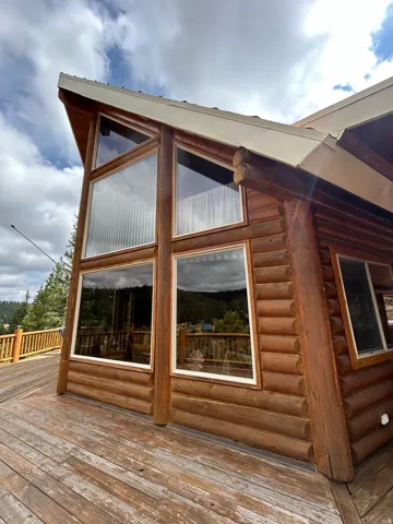 Log cabin exterior featuring a multi-level deck, large picture windows, and a prominent A-frame architectural style