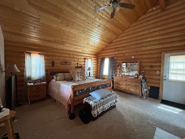 Vaulted wood-paneled ceiling, wood-finished walls, and light-toned carpeting