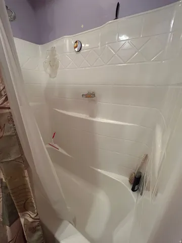 White acrylic tub and shower combination with integrated shelving