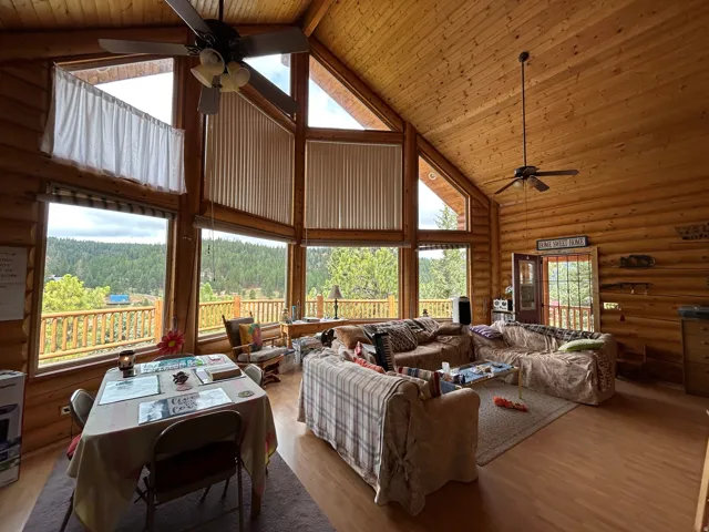 Vaulted wood-paneled ceiling, exposed log walls, ample natural light, wood-finish flooring, and a glass-paneled exterior door