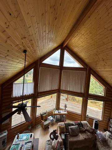 Vaulted wood-paneled ceiling, exposed wood beams, extensive window array, and large outdoor deck