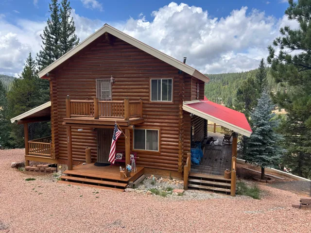 Log-sided exterior with a prominent A-frame roofline and red metal roofing