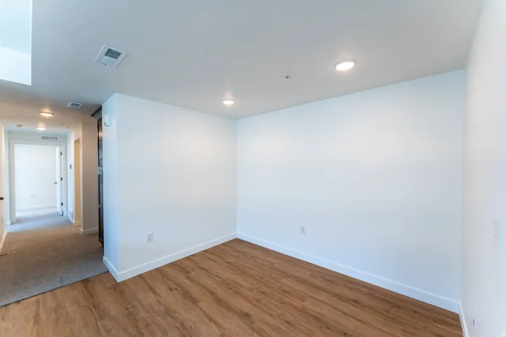 Wood-finish flooring with white walls and recessed ceiling lighting