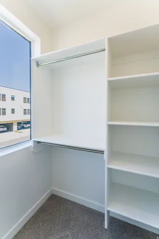 Built-in closet system with hanging rods, integrated shelving, and carpeted flooring