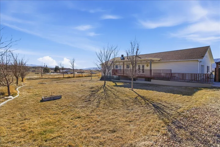 Expansive yard space with a gravel path, a stone-lined garden bed, and a long wooden deck with a railing