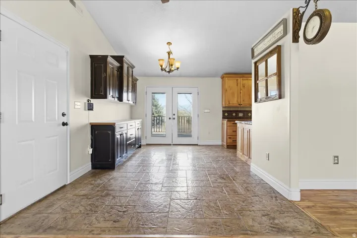 Vaulted ceiling, stamped tile flooring, French doors, built-in cabinetry, and a chandelier
