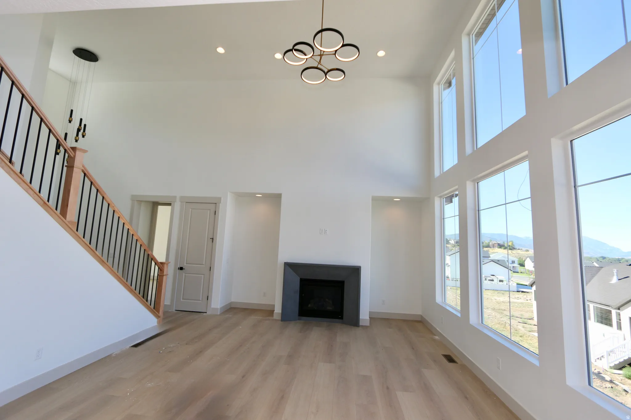 Two-story living area featuring a modern linear fireplace, wood-finish flooring, and high ceilings and expansive views