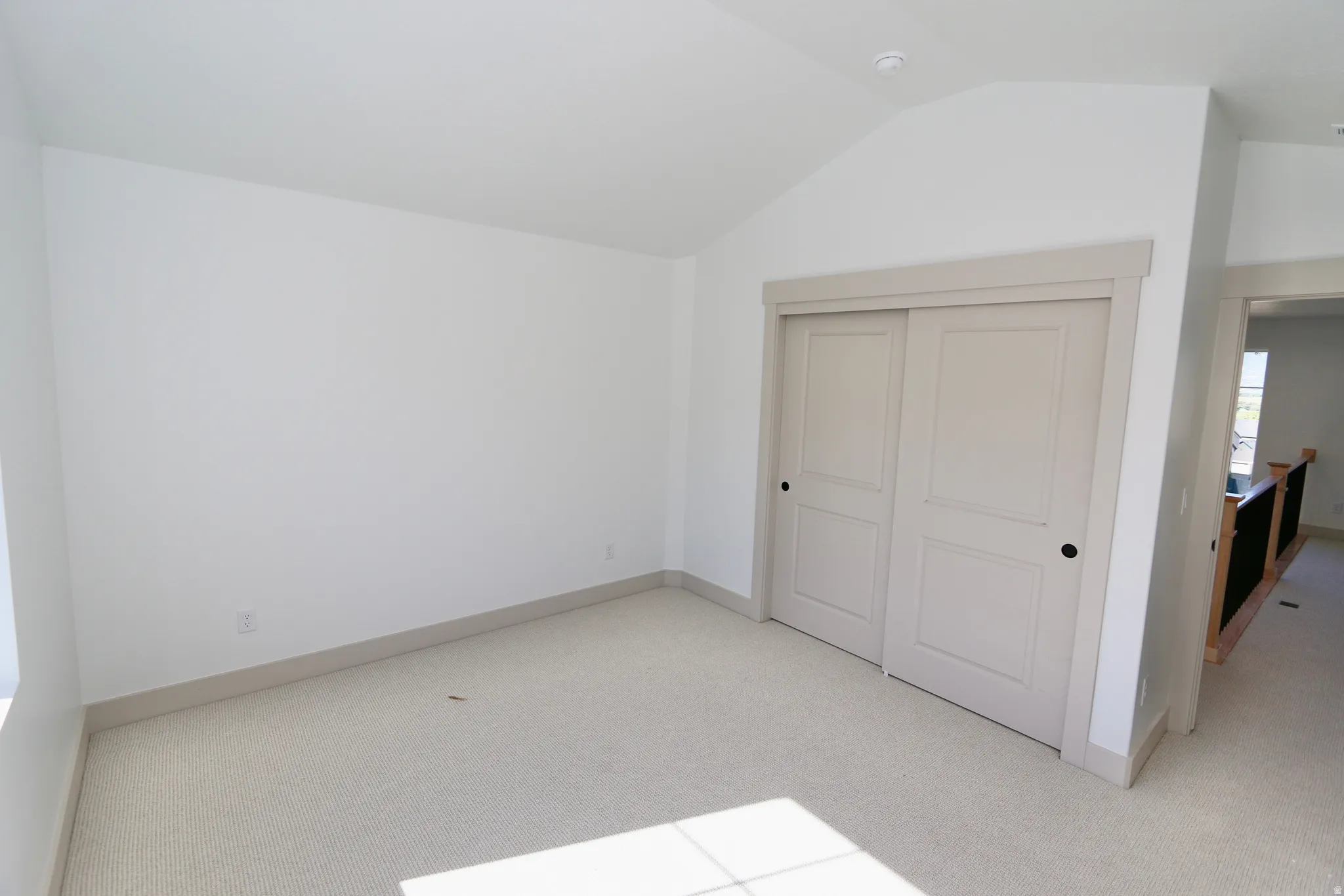Vaulted ceiling with recessed lighting, light-toned carpeting, and a large closet