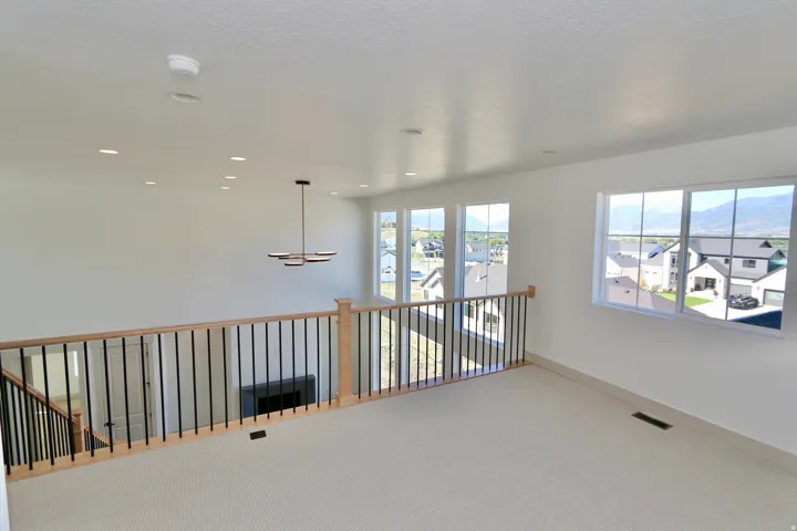 Open concept loft space featuring carpeted flooring, multiple recessed lights, and large windows with mountain scenery