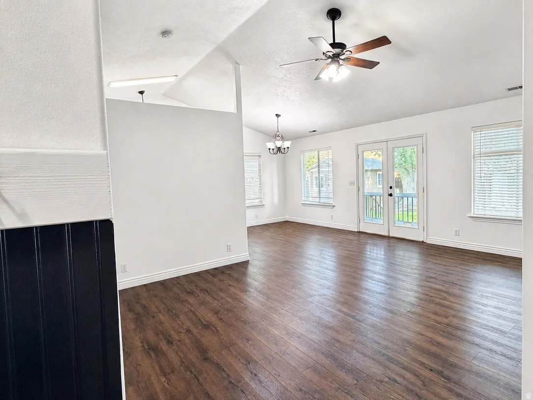 Vaulted ceilings with a ceiling fan, wood-finish flooring, white walls, and French doors