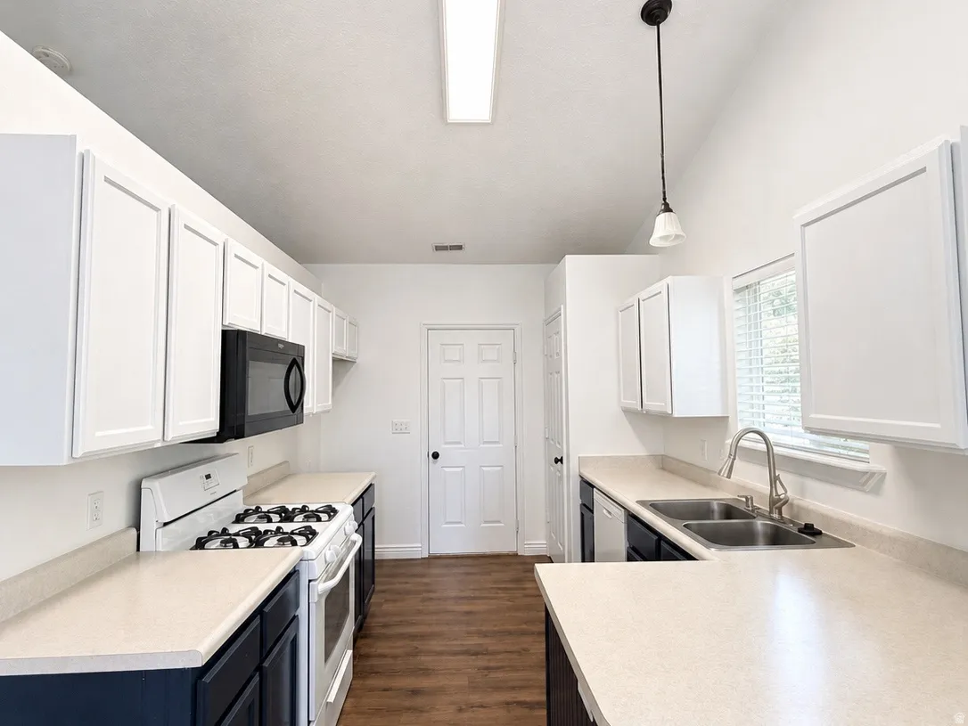 Vaulted ceilings, wood-finish flooring, white upper cabinetry, two-tone cabinetry, and a double basin sink