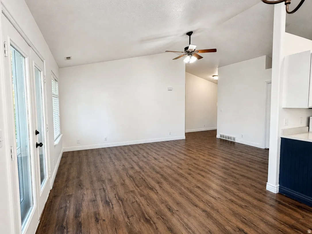 Vaulted ceiling with a ceiling fan, wood-finish flooring, white walls, and white French doors